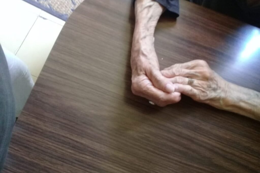 Mani rugose di una donna anziana appoggiate una sull'altra